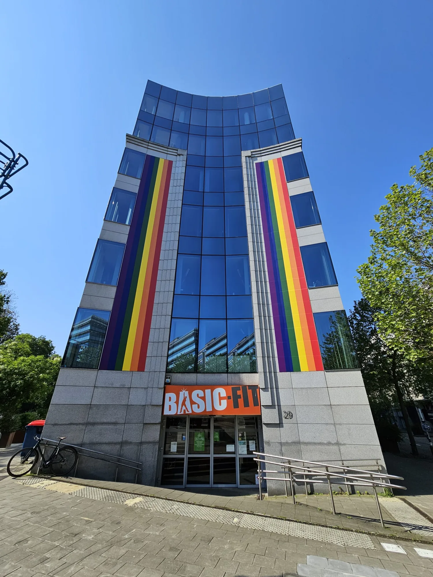 Kantoortoren met twee grote, regenboogkleurige banners langs de gevel