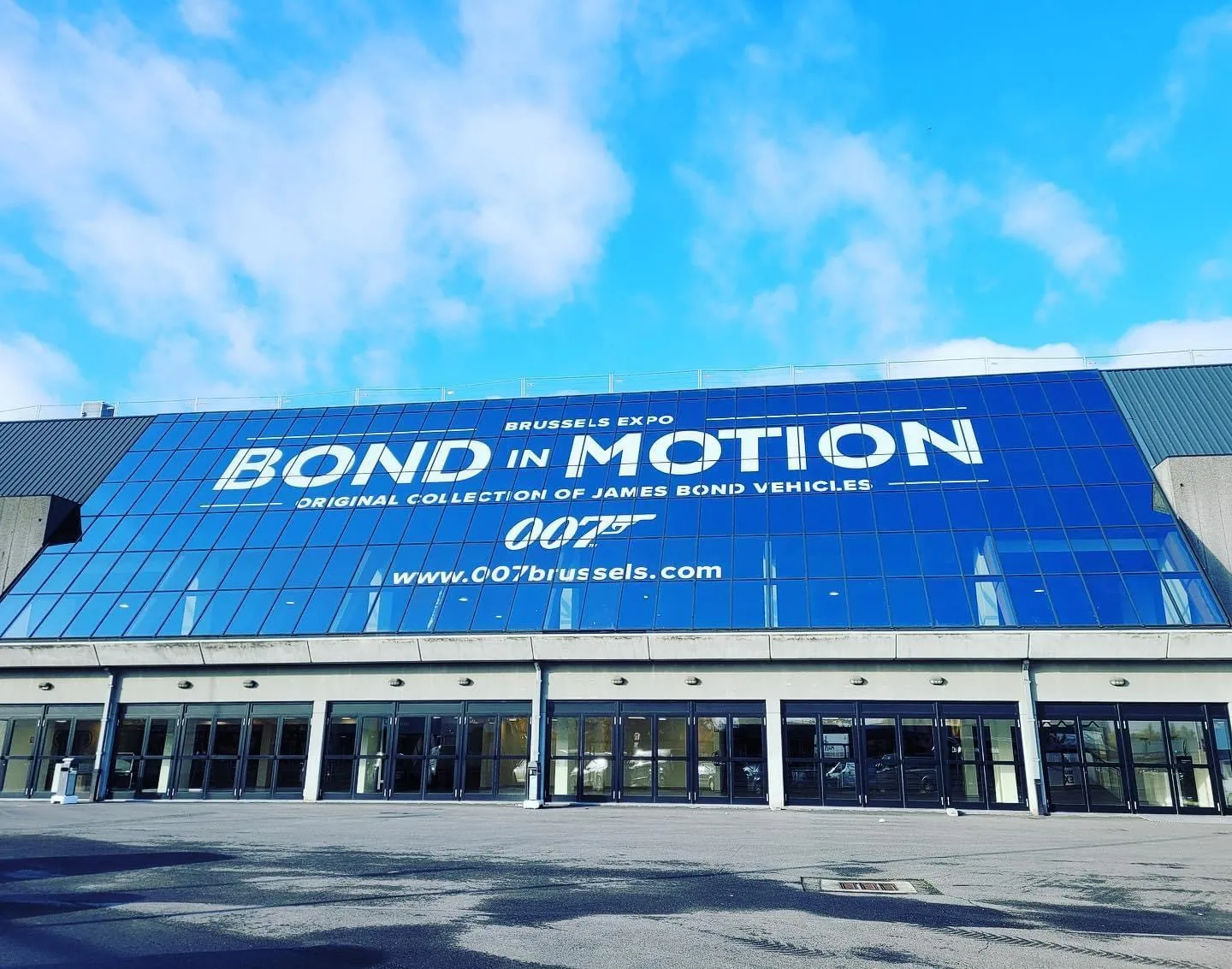 Gevel van een tentoonstellingshal volledig bedekt met een blauwe megabanner