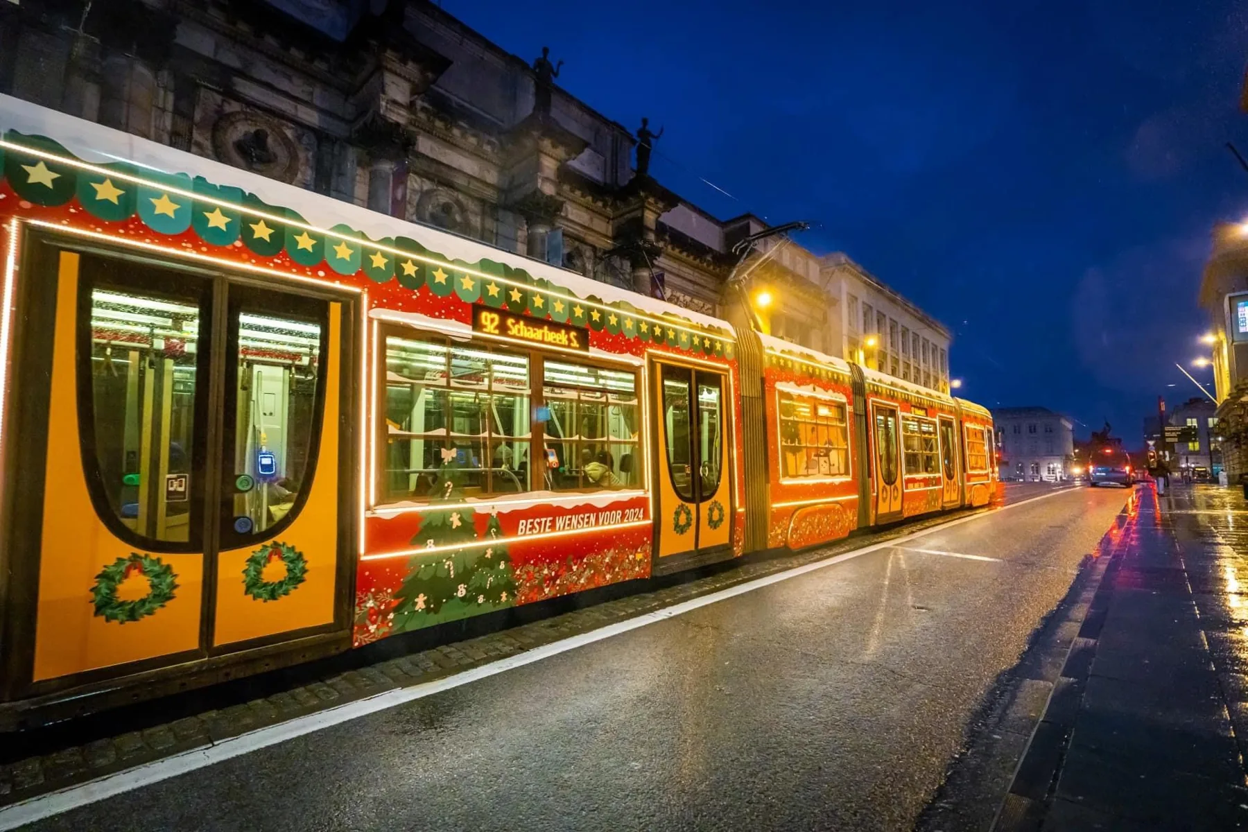 Tram met feestelijke wrap rijdt door de stad bij valavond